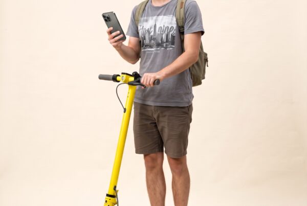 Portrait studio : jeune touriste en tongs sur une trottinette électrique de location jaune, téléphone en main