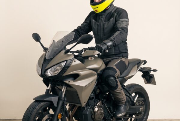 Portrait studio : motard casque intégral jaune sur sa moto sport-touring, prêt à partir